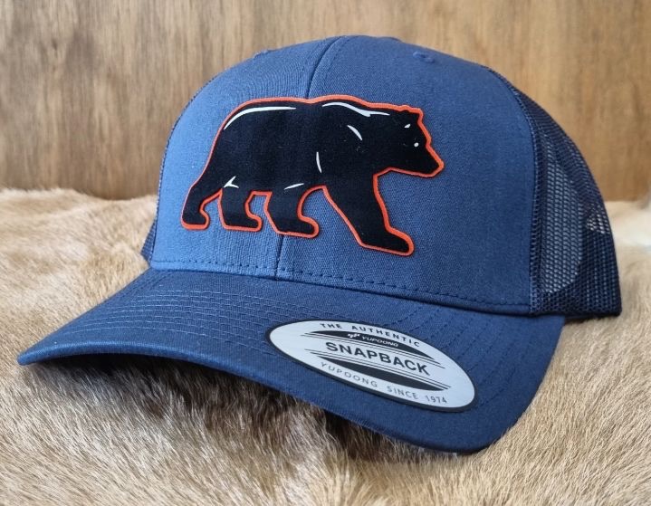 Gorra trucker azul marino con el oso de Arteaga delineado en naranja